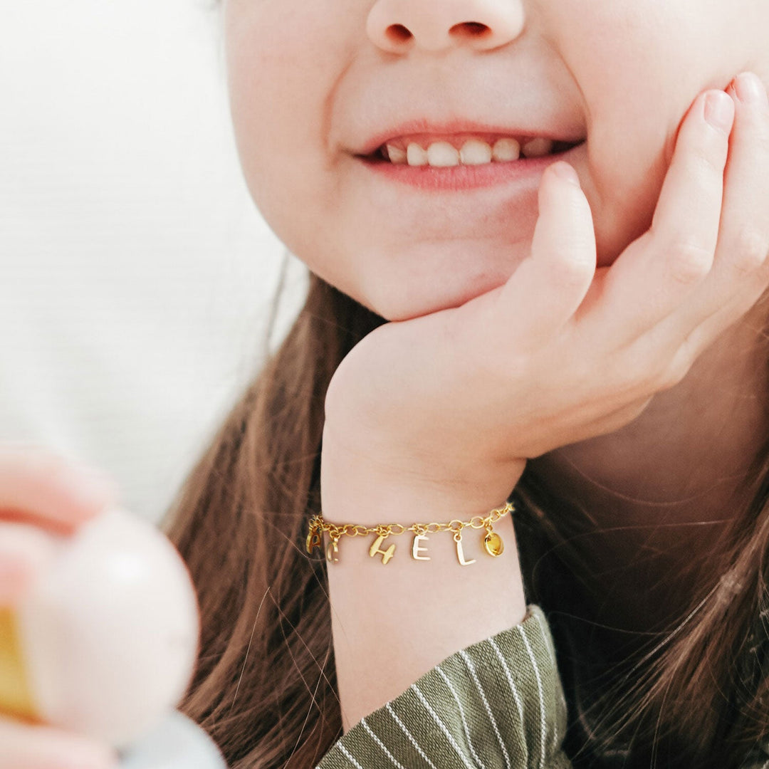Gold Personalized Childrens Letters and Birthstone Pendant Bracelet Worn on Girls Hand