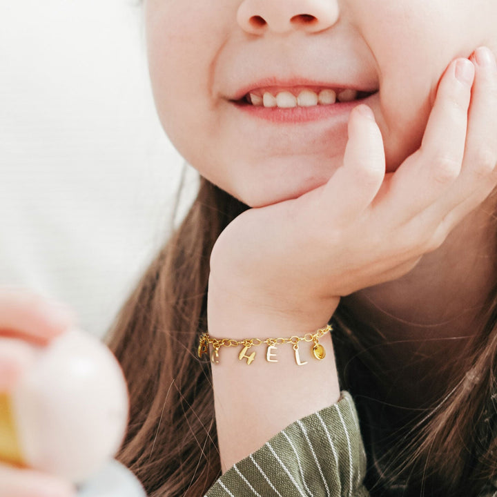 Gold Personalized Childrens Letters and Birthstone Pendant Bracelet Worn on Girls Hand
